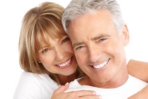 A couple smiles in front of a white backdrop | Crowns and Bridges humble TX