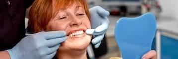 woman smiling in a dental mirror