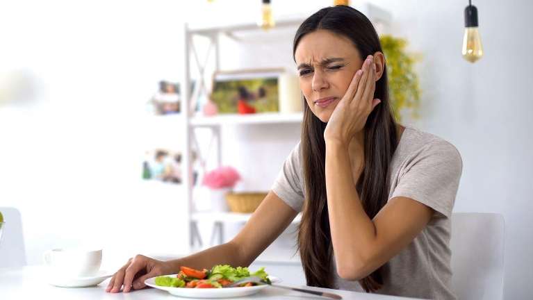 Woman suffering tooth ache while eating in Humble TX